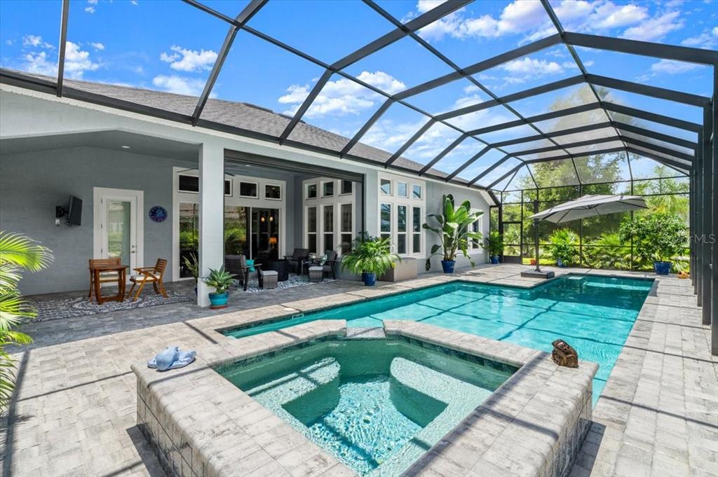 A screened-in patio features a swimming pool, a raised spa, and stone paver flooring — 2426 WILD TURKEY CREEK LN, PORT ORANGE, FL