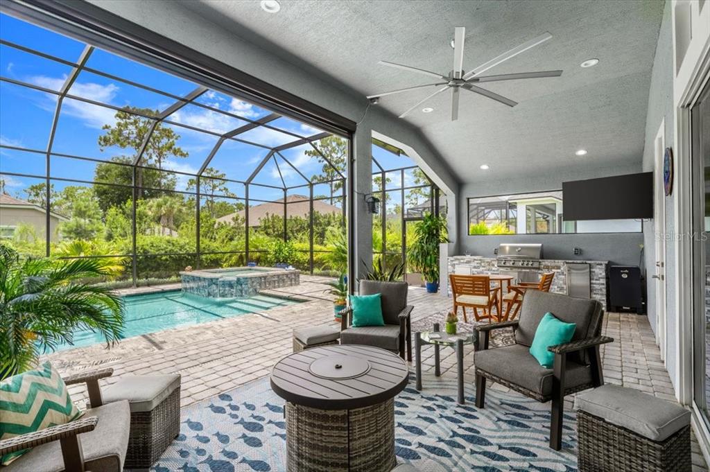A covered patio features a pool, hot tub, outdoor kitchen, and seating area with furniture — 2426 WILD TURKEY CREEK LN, PORT ORANGE, FL