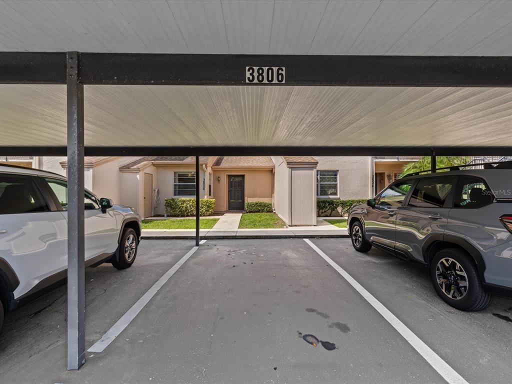A covered carport sits in front of a residential building with two parked cars — 3806 STAYSAIL LANE, HOLIDAY, FL
