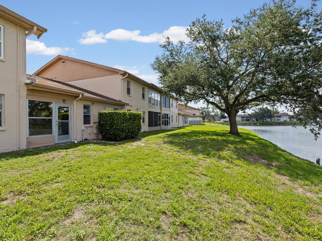 A multi-story apartment building sits next to a grassy lawn and a lake — 3806 STAYSAIL LANE, HOLIDAY, FL