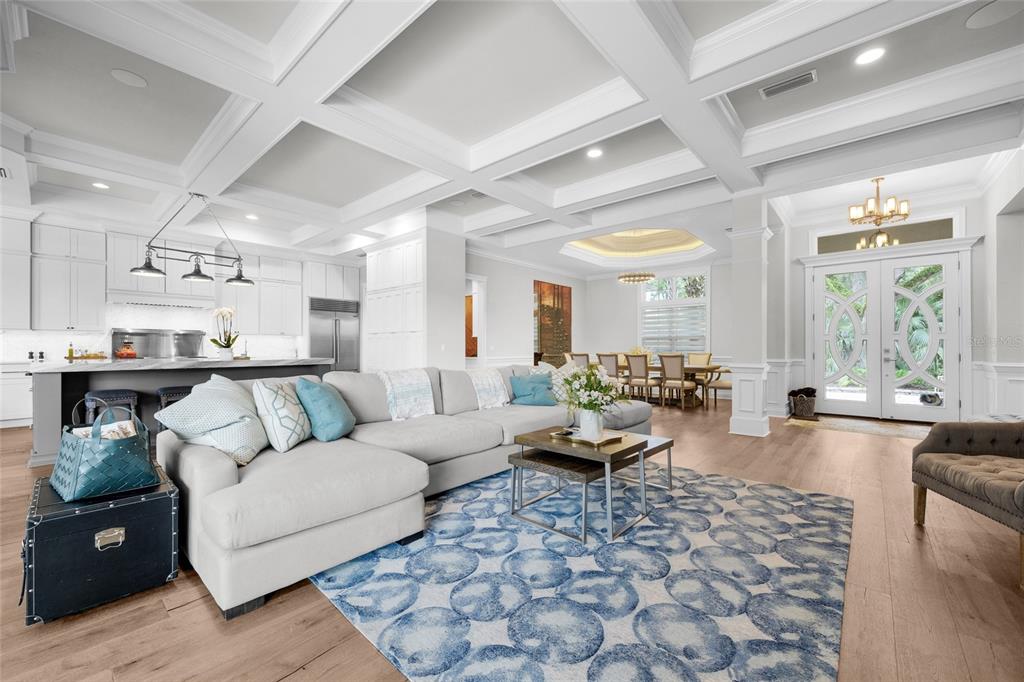 A spacious open-concept living room features a coffered ceiling, hardwood floors, and a large sectional — 11372 SW 30TH AVENUE, GAINESVILLE, FL