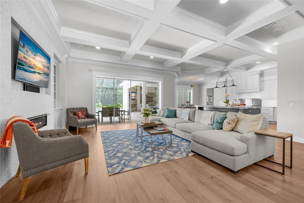 A living room with a coffered ceiling, fireplace, large sectional sofa, and sliding glass doors — 11372 SW 30TH AVENUE, GAINESVILLE, FL