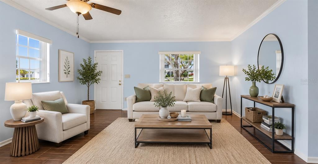 A living room features light blue walls, a beige sofa, an armchair, and wood flooring — 6643 KELSEY LANE UNIT 4B, NEW PORT RICHEY, FL