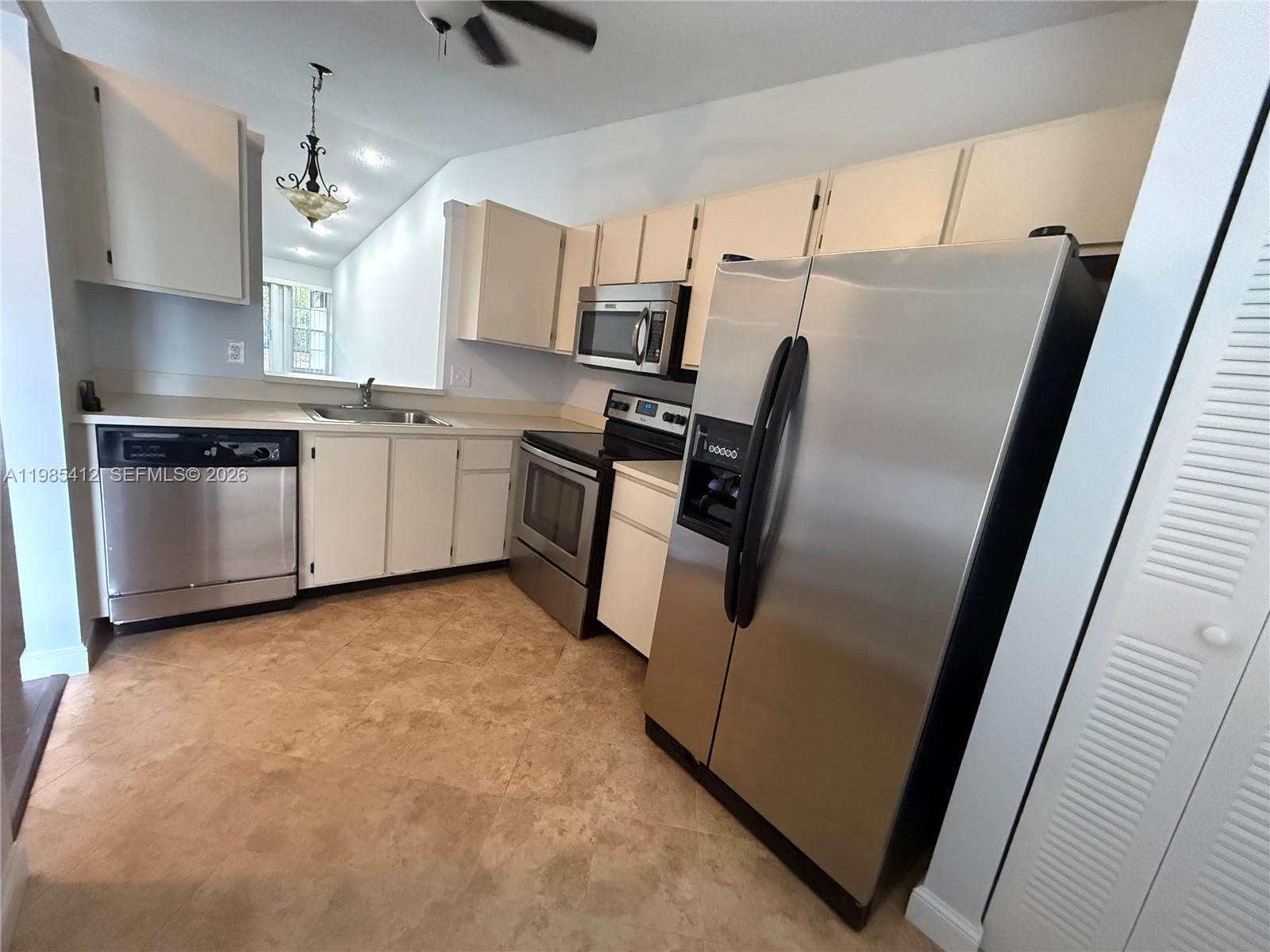 A kitchen features white cabinets, stainless steel appliances, and light-colored tile flooring — 18595 Egret Way # 18595, Boca Raton FL 33496, BOCA RATON, FL
