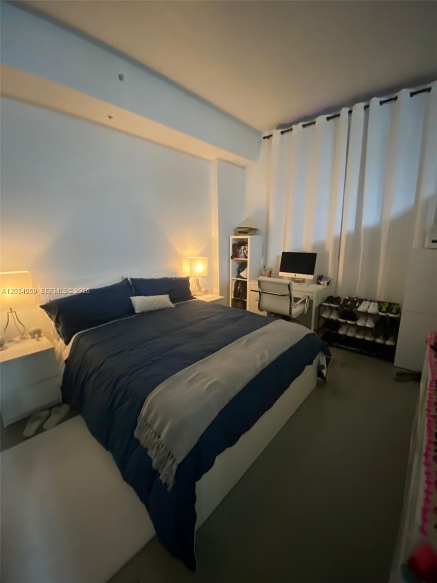 A bedroom features a bed with blue bedding, a desk, and a shoe rack — 133 NE 2nd Ave # 2805, Miami FL 33132, MIAMI, FL