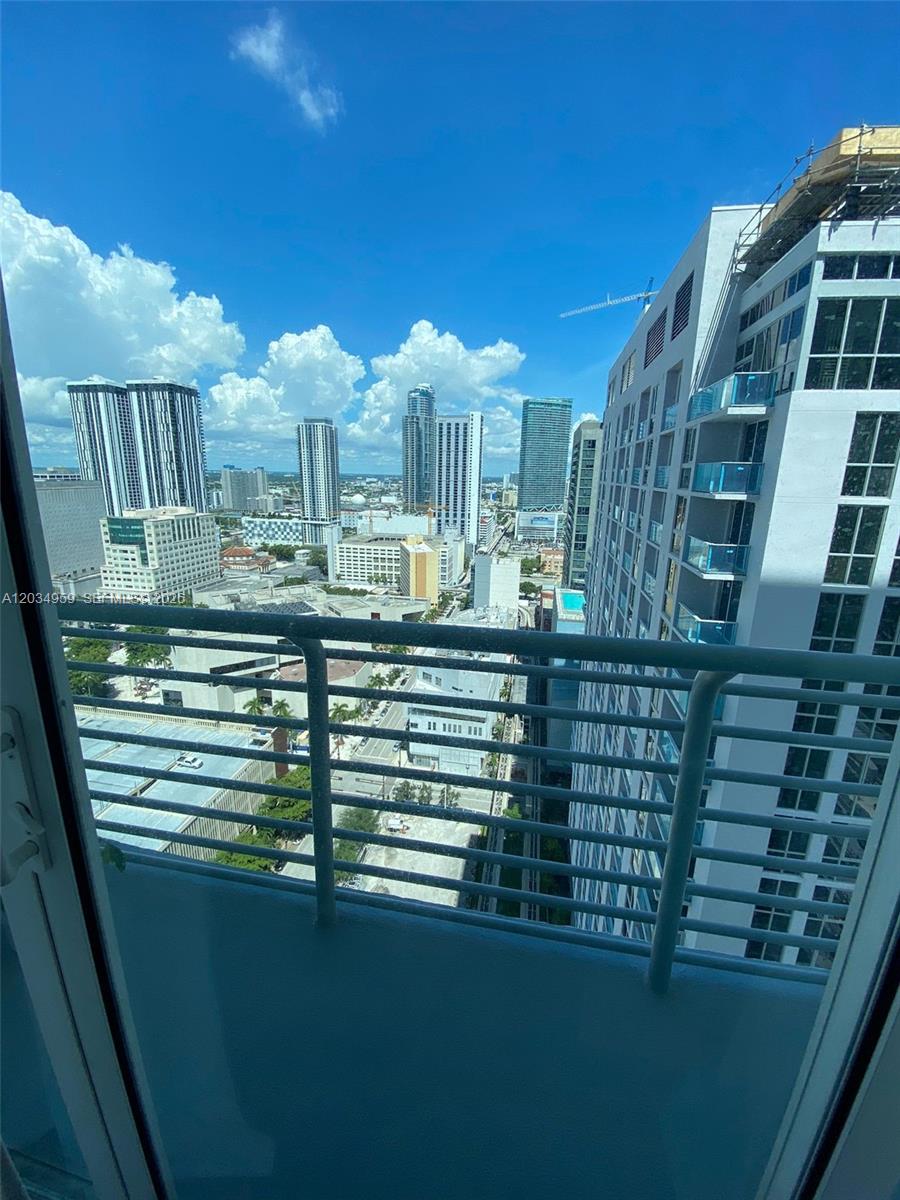 A high-rise balcony overlooks a dense urban cityscape with multiple skyscrapers under a blue sky — 133 NE 2nd Ave # 2805, Miami FL 33132, MIAMI, FL