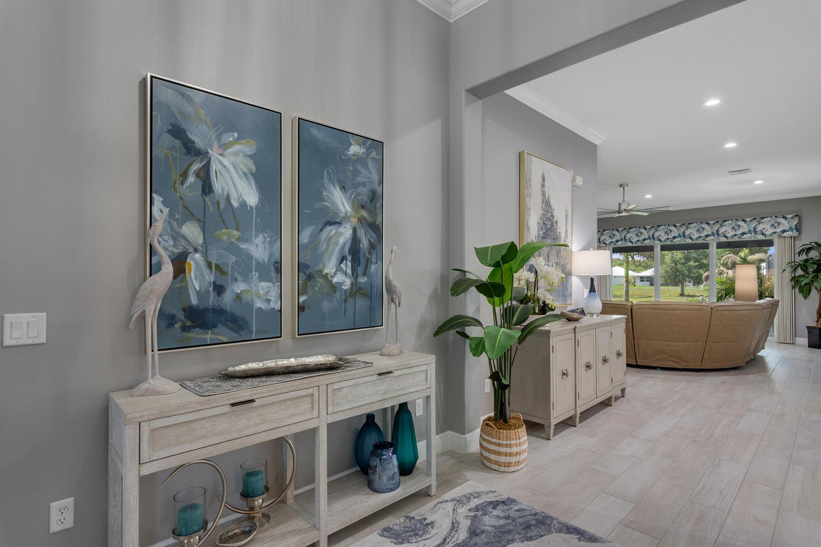 A foyer features a console table with blue decor, wall art, and a view into the living room — 5625 Arabella Lane, Vero Beach FL 32967, VERO BEACH, FL