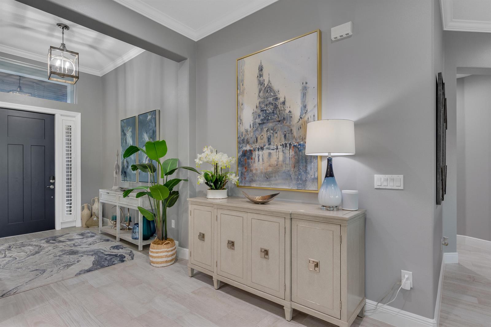 A bright entryway features a light-colored console table, a large framed painting, and a lamp — 5625 Arabella Lane, Vero Beach FL 32967, VERO BEACH, FL
