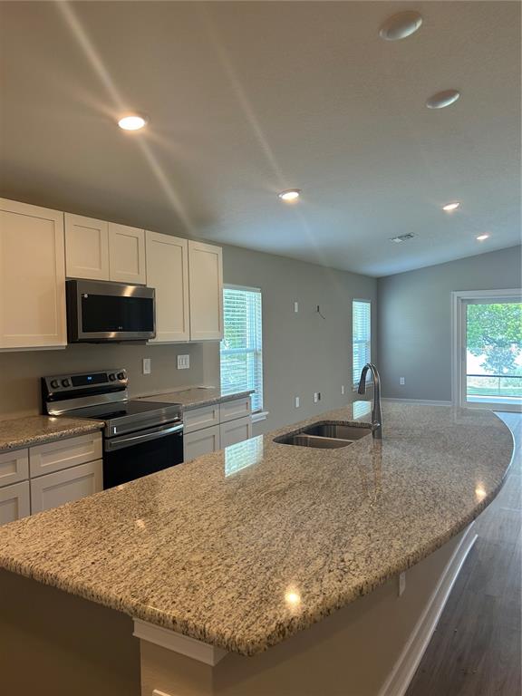 A kitchen features white cabinets, granite countertops, a large island, and stainless steel appliances — 373 W MAIN STREET, HAINES CITY, FL