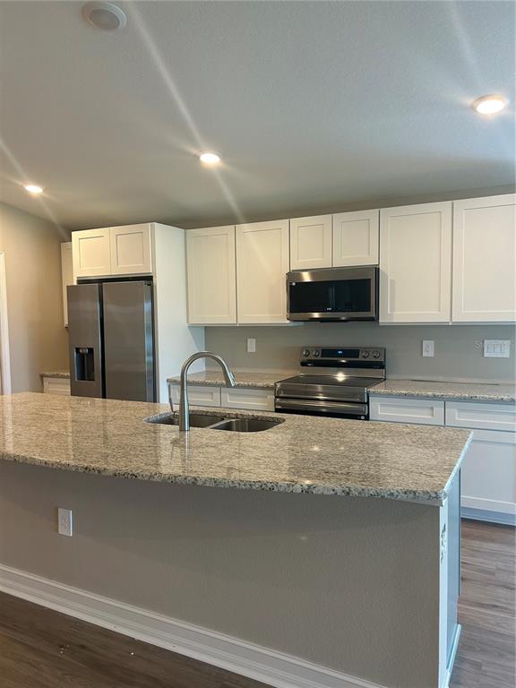 A kitchen features white cabinets, stainless steel appliances, a granite island, and a double sink — 373 W MAIN STREET, HAINES CITY, FL