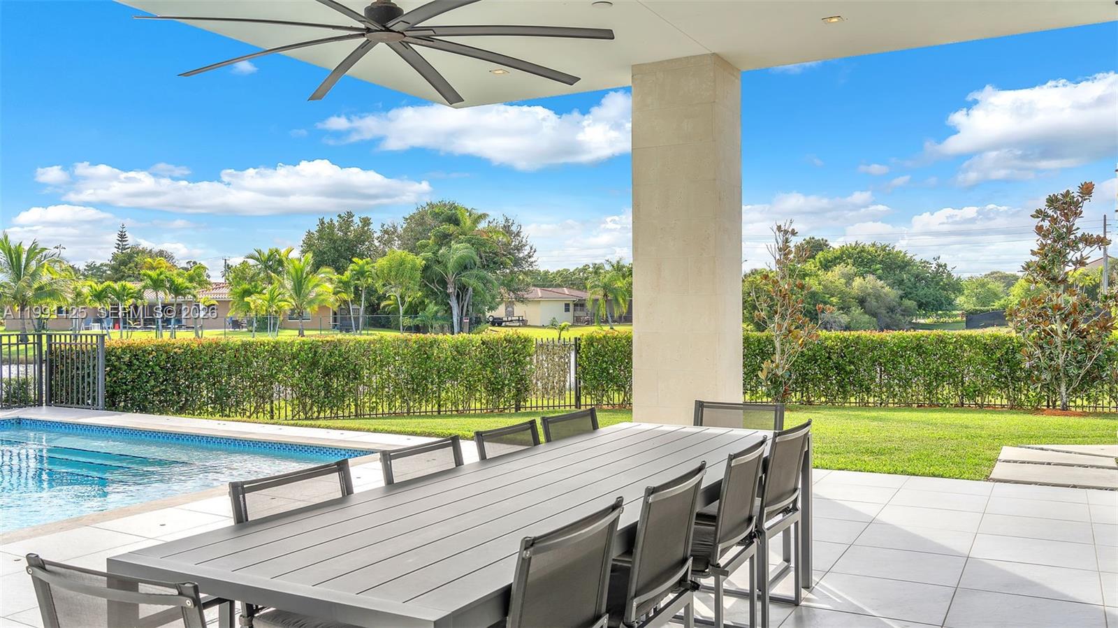 A covered patio features a dining table, a ceiling fan, and a view of a pool — 16772 Botaniko Dr S, Weston FL 33326, WESTON, FL