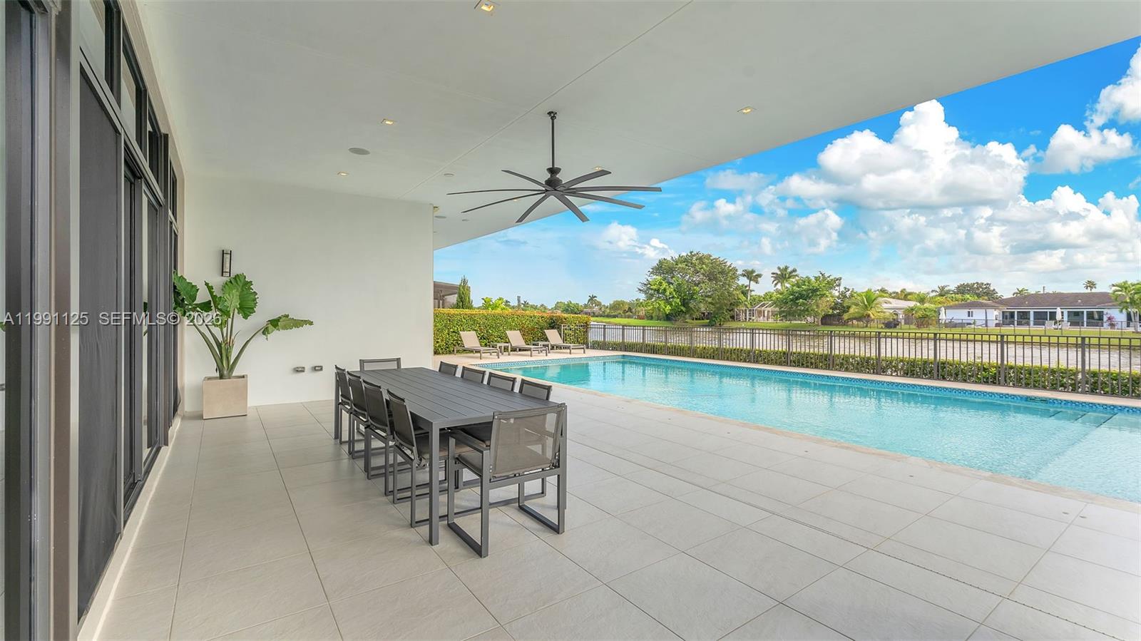 A covered patio features a dining table, a ceiling fan, and a swimming pool — 16772 Botaniko Dr S, Weston FL 33326, WESTON, FL
