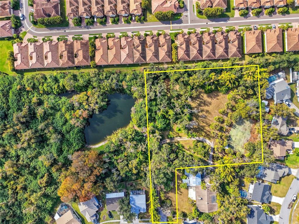 An aerial view shows a residential lot outlined in yellow, featuring trees and a pond — 7808 34TH COURT E, SARASOTA, FL