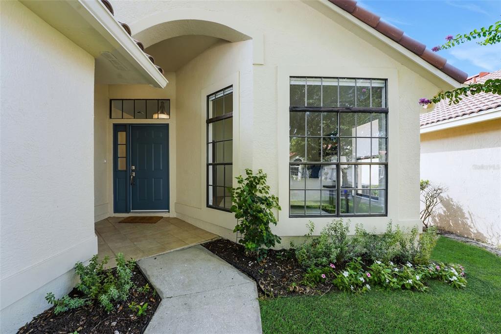 The exterior of a house features a blue front door, a tiled entryway, and windows — 1329 AUGUSTA NATIONAL BOULEVARD, WINTER SPRINGS, FL