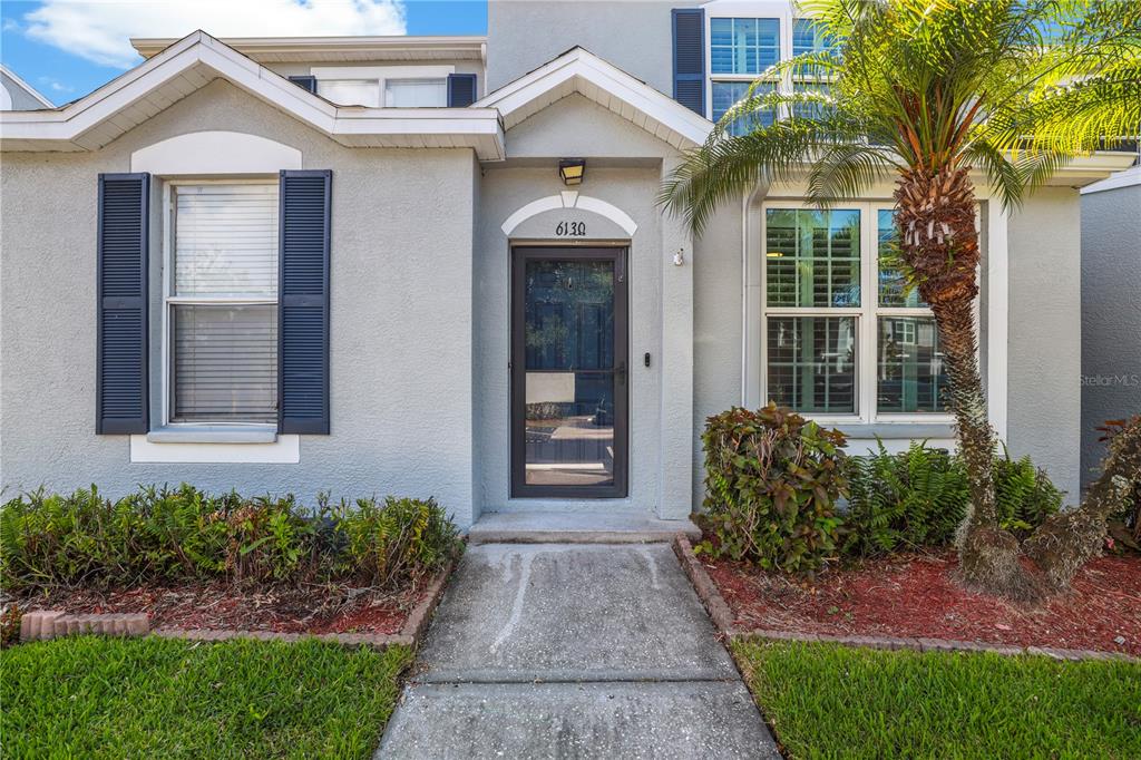 A gray stucco house exterior features a front door, a walkway, and a palm tree — 6130 OSPREY LAKE CIRCLE, RIVERVIEW, FL