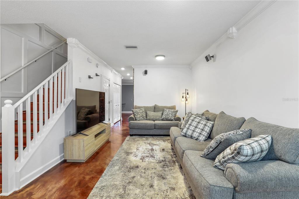 A living room features a staircase, gray sofas, a television, and wood-look flooring — 6130 OSPREY LAKE CIRCLE, RIVERVIEW, FL