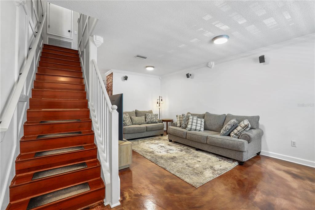 A living room with wood stairs, gray sofas, and stained concrete floors — 6130 OSPREY LAKE CIRCLE, RIVERVIEW, FL