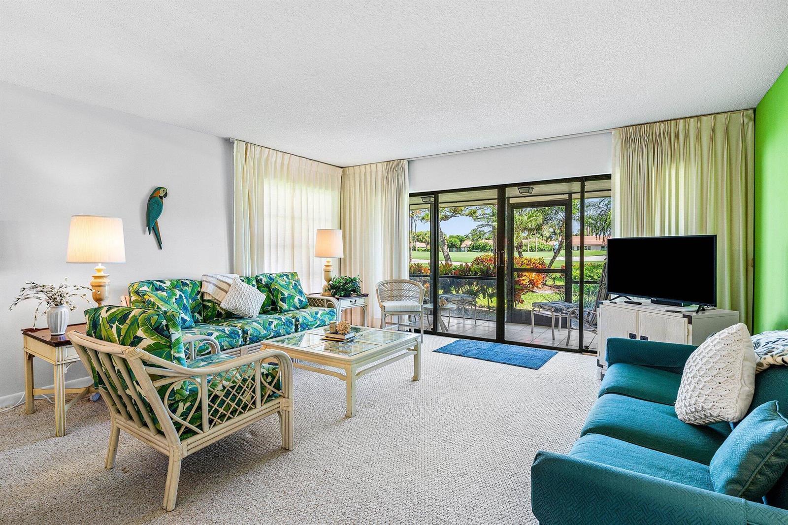 A living room features a tropical-print sofa, a teal sofa, and sliding glass doors — 4085 Kittiwake Court, Boynton Beach FL 33436, BOYNTON BEACH, FL