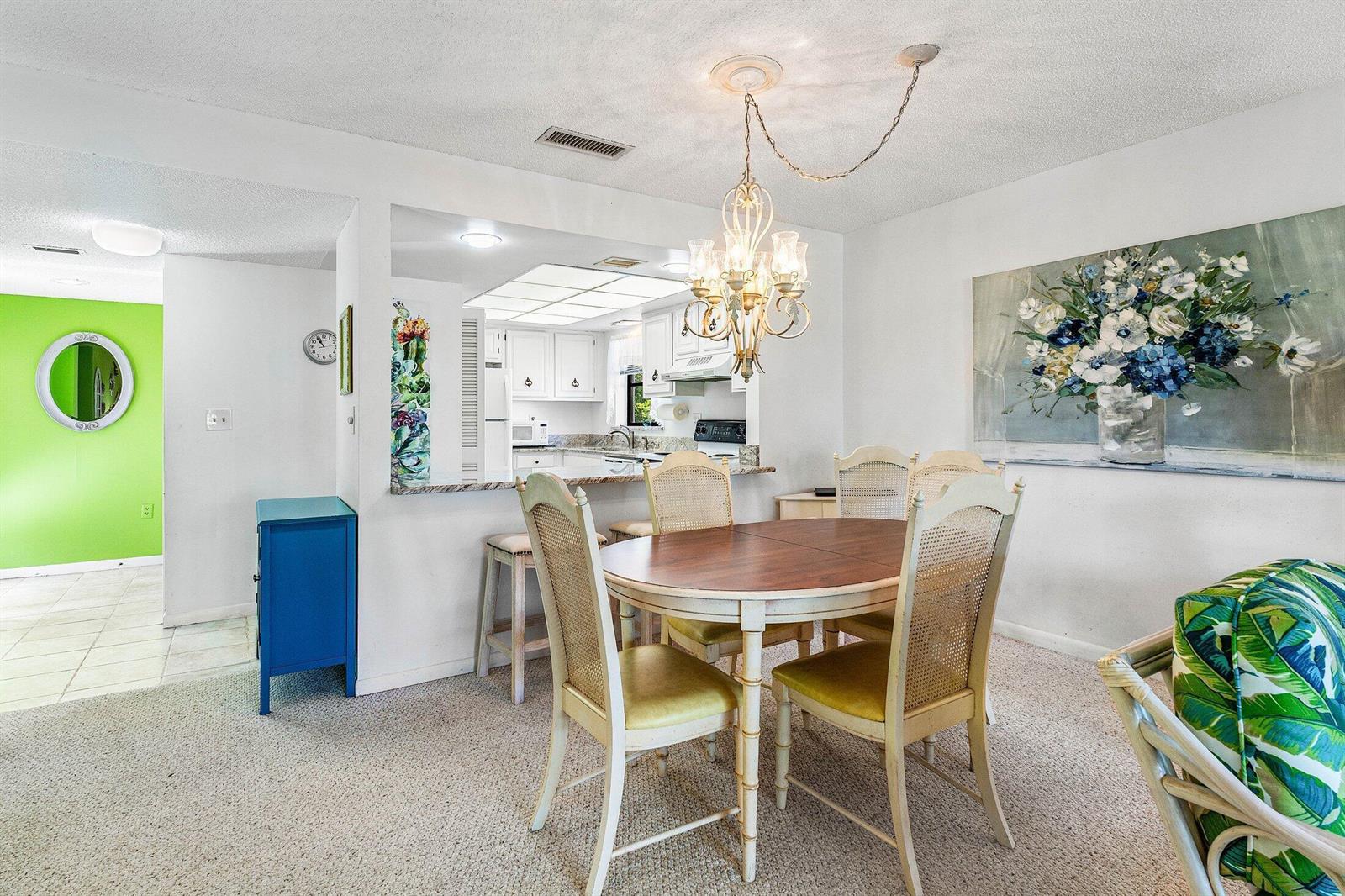 A dining area with a round table, chandelier, and a breakfast bar overlooking the kitchen — 4085 Kittiwake Court, Boynton Beach FL 33436, BOYNTON BEACH, FL