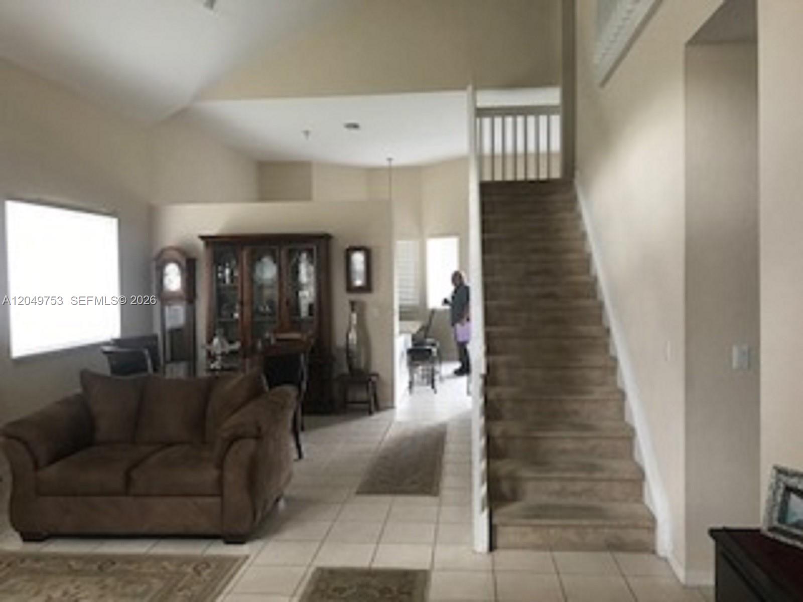 A living room features a brown sofa, a wooden hutch, and carpeted stairs — 1870 SE 18th Ter, Homestead FL 33035, HOMESTEAD, FL