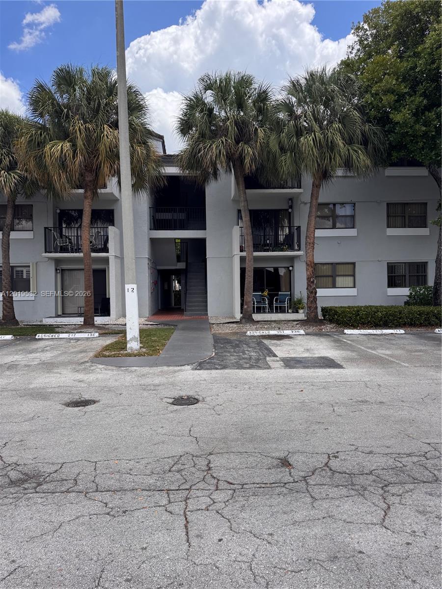 A three-story apartment building exterior features palm trees, balconies, and a paved parking lot — 7115 NW 179th St # 207, Hialeah FL 33015, HIALEAH, FL