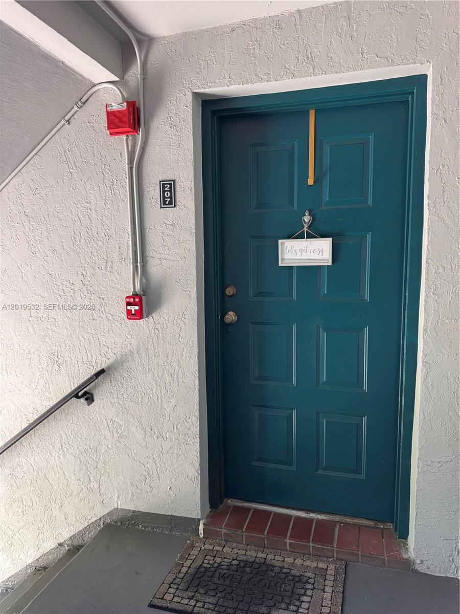A teal apartment door with a sign and a fire alarm system on the wall — 7115 NW 179th St # 207, Hialeah FL 33015, HIALEAH, FL
