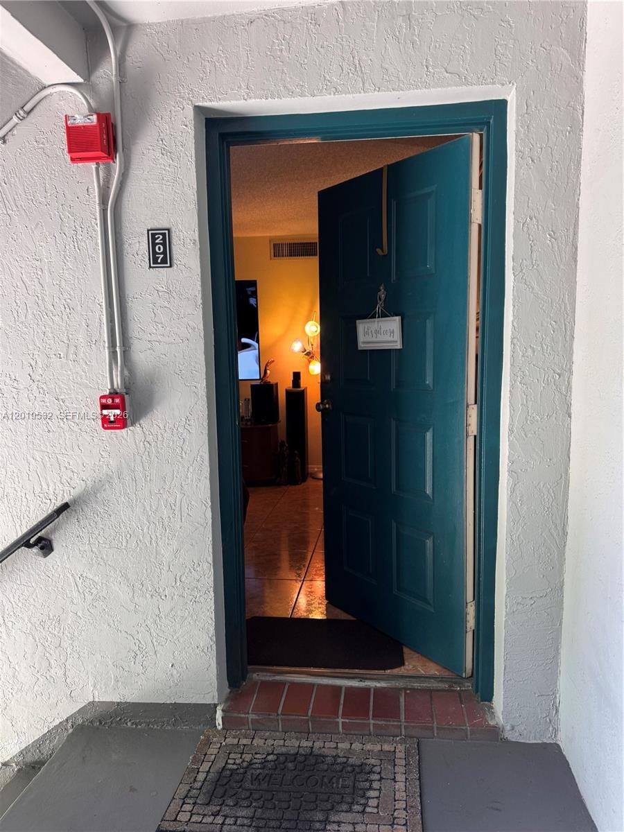 An open teal door leads into a room with tile flooring and warm lighting — 7115 NW 179th St # 207, Hialeah FL 33015, HIALEAH, FL