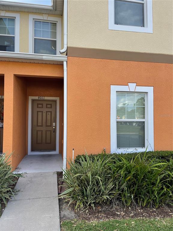 The exterior of a two-story orange stucco townhouse features a brown front door and windows — 4011 WINDING VINE DRIVE, LAKELAND, FL