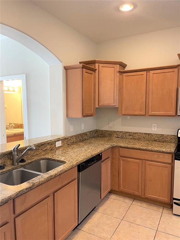 A kitchen features light wood cabinets, granite countertops, a double sink, and tile flooring — 4011 WINDING VINE DRIVE, LAKELAND, FL