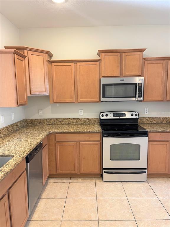 A kitchen features light wood cabinets, granite countertops, and stainless steel appliances — 4011 WINDING VINE DRIVE, LAKELAND, FL