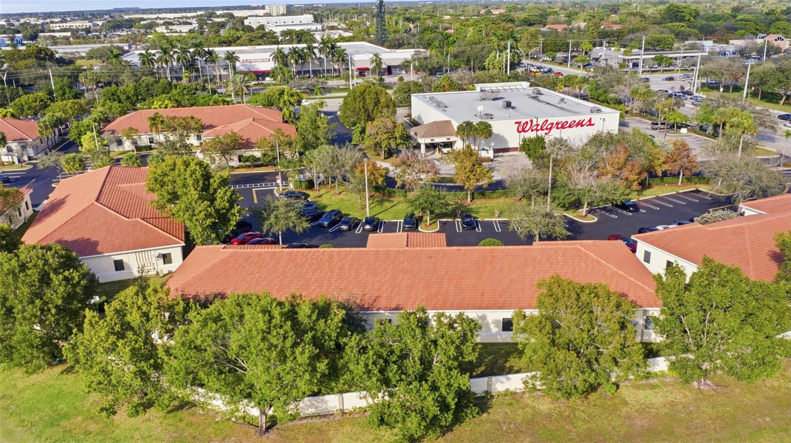 An aerial view shows a commercial complex with red-tiled roofs and a Walgreens store — CORAL SPRINGS, FL