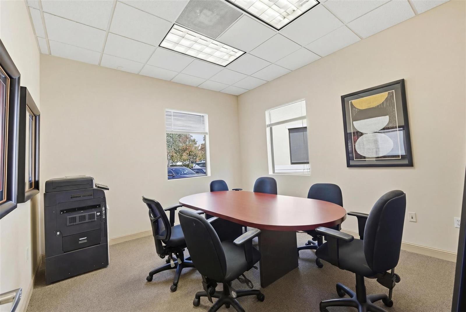 A small office conference room features a wooden oval table, six chairs, and a printer — CORAL SPRINGS, FL