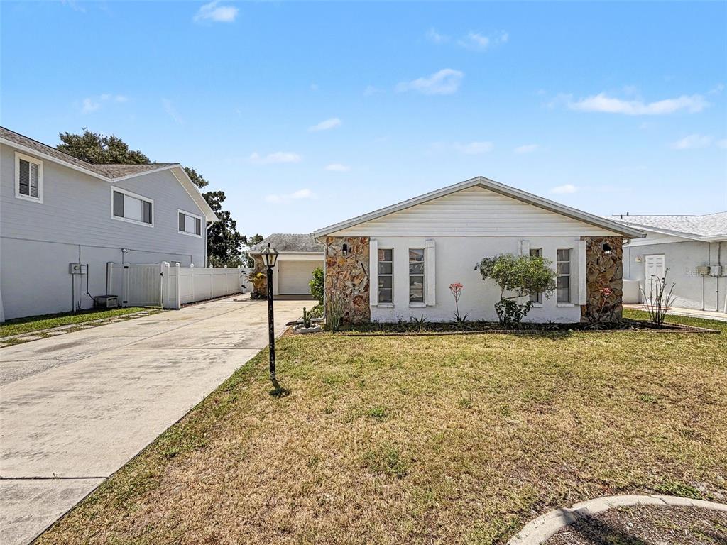 A single-story house with a stone facade and a long concrete driveway — 7038 SOUTHWIND DRIVE, HUDSON, FL