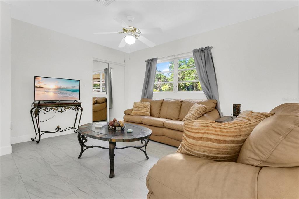 A living room features light tile flooring, a tan sofa, a coffee table, and a television — 1801 EASTERN AVENUE, ST CLOUD, FL