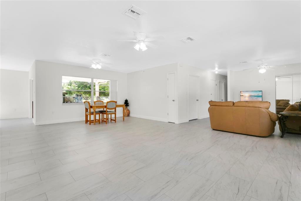 A spacious, open-concept living and dining area features light-colored tile flooring and white walls — 1801 EASTERN AVENUE, ST CLOUD, FL