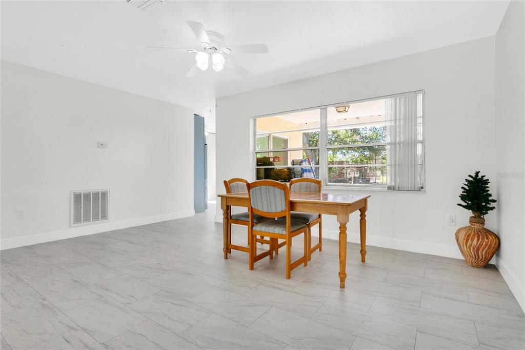 A dining room with light gray tile flooring, a wooden table, and a ceiling fan — 1801 EASTERN AVENUE, ST CLOUD, FL