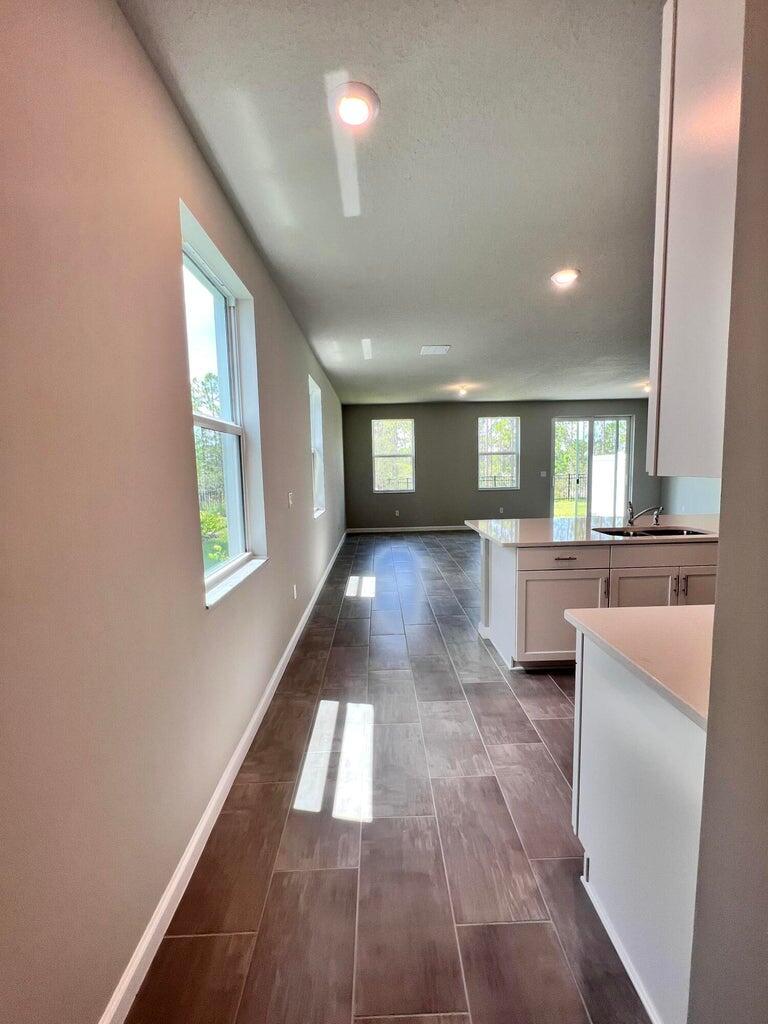 A kitchen with white cabinets and an island overlooks a living area with tiled floors — 254 Osprey Preserve Boulevard, Jensen Beach FL 34957, JENSEN BEACH, FL