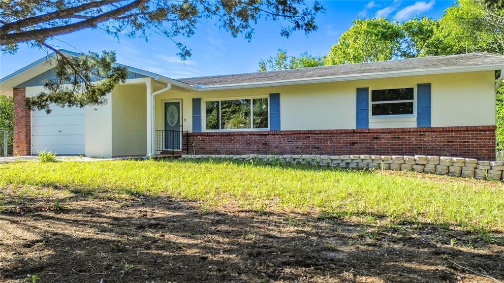 A single-story house with a brick base, light-colored siding, blue shutters, and an attached garage — 6 OKLAHOMA STREET, BEVERLY HILLS, FL