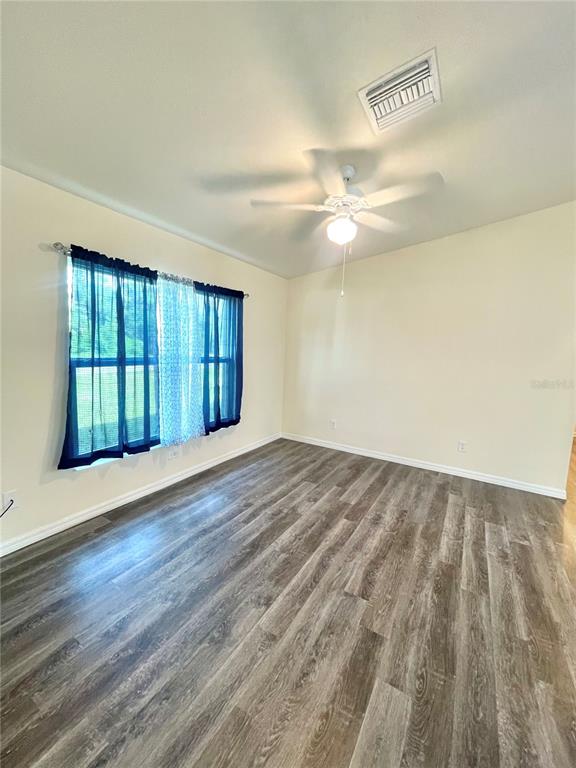 An empty room features light-colored walls, a ceiling fan, and wood-look vinyl plank flooring — 5029 W HUMMINGBIRD DRIVE, LABELLE, FL