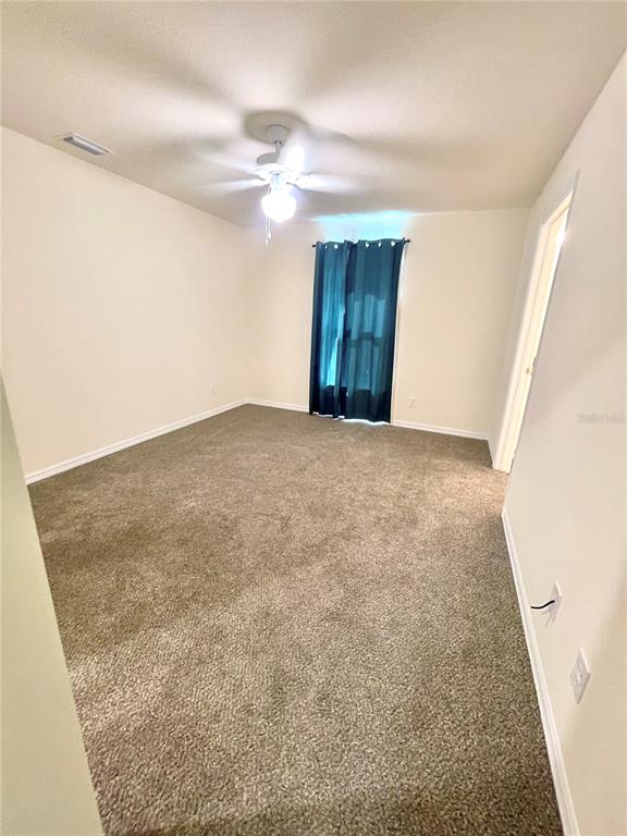 An empty bedroom features beige walls, brown carpeting, a ceiling fan, and a teal curtain — 5029 W HUMMINGBIRD DRIVE, LABELLE, FL