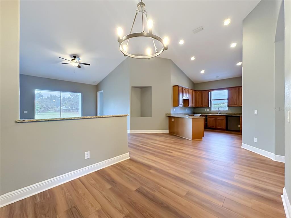 An open-concept kitchen and living area features wood-look flooring, vaulted ceilings, and wooden cabinets — 28549 SHIRLEY SHORES ROAD, TAVARES, FL