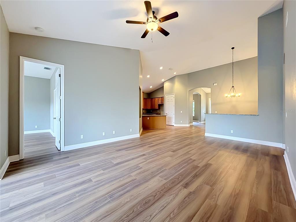 An open-concept living area features light gray walls, wood-look flooring, and a ceiling fan — 28549 SHIRLEY SHORES ROAD, TAVARES, FL