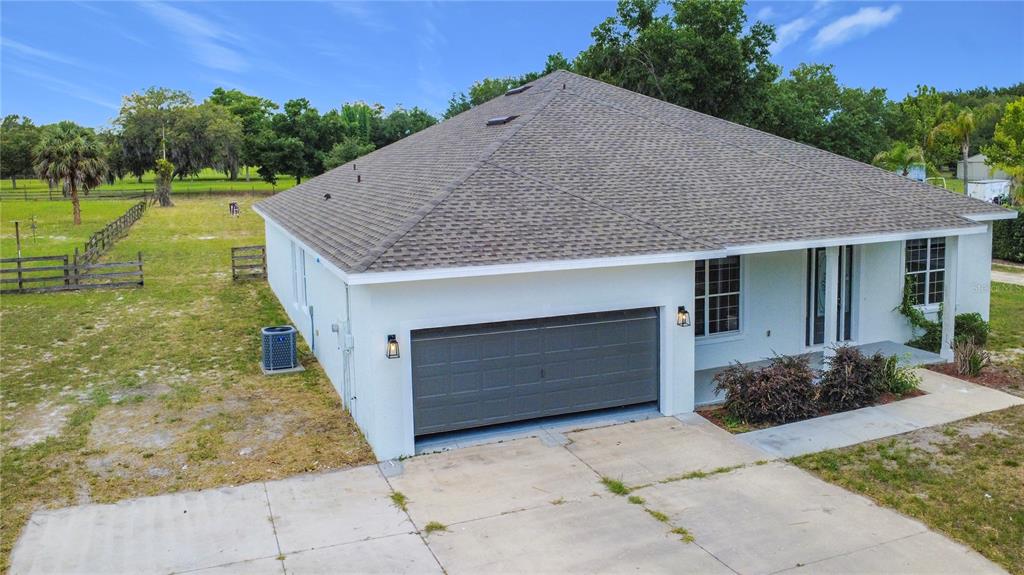 A white single-story house with a gray shingled roof and an attached two-car garage — 28549 SHIRLEY SHORES ROAD, TAVARES, FL