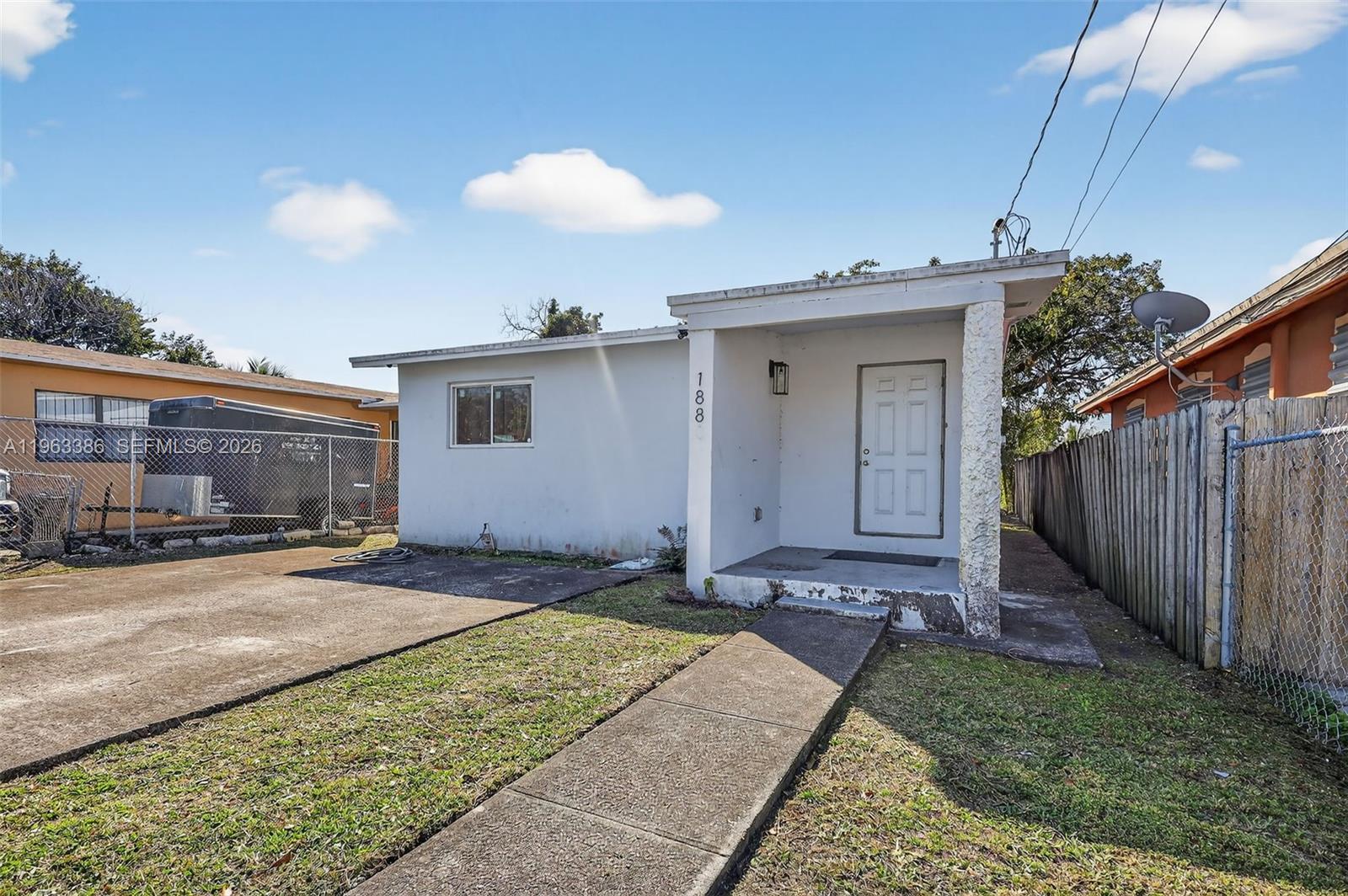 A small, white, single-story house features a concrete walkway leading to a covered front entrance — 1880 NW 69th St, Miami FL 33147, MIAMI, FL