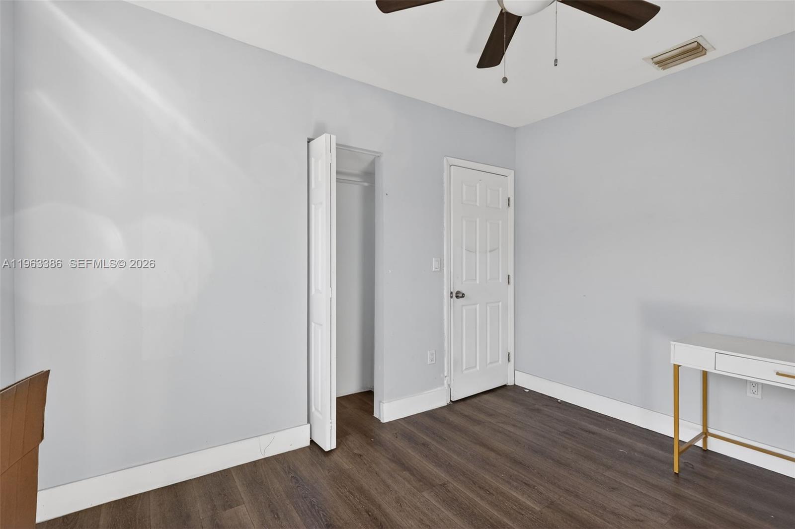 This bedroom features light gray walls, dark wood-look flooring, a closet, and a white desk — 1880 NW 69th St, Miami FL 33147, MIAMI, FL