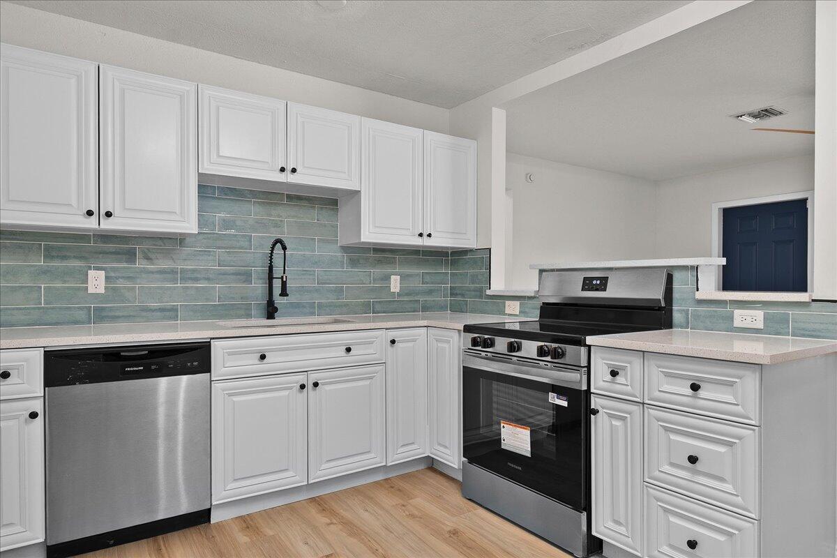 A kitchen features white cabinets, stainless steel appliances, and a blue subway tile backsplash — 1414 S N Street, FL 33460, FL