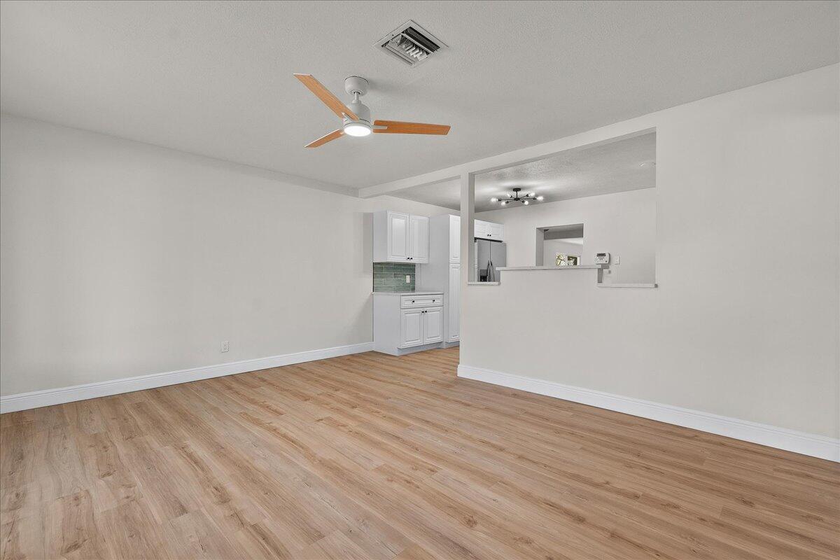 An open living area with light wood-look flooring, a ceiling fan, and a kitchen pass-through — 1414 S N Street, FL 33460, FL