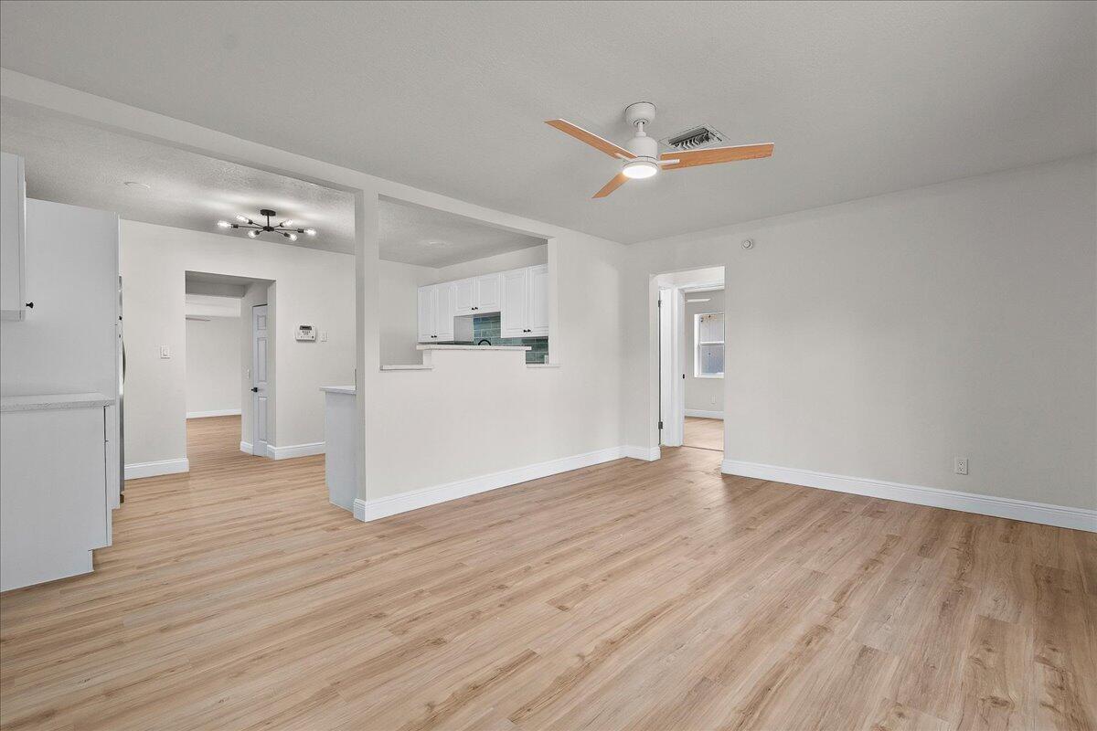 An open-concept living area features light wood-look flooring, white walls, and a ceiling fan — 1414 S N Street, FL 33460, FL