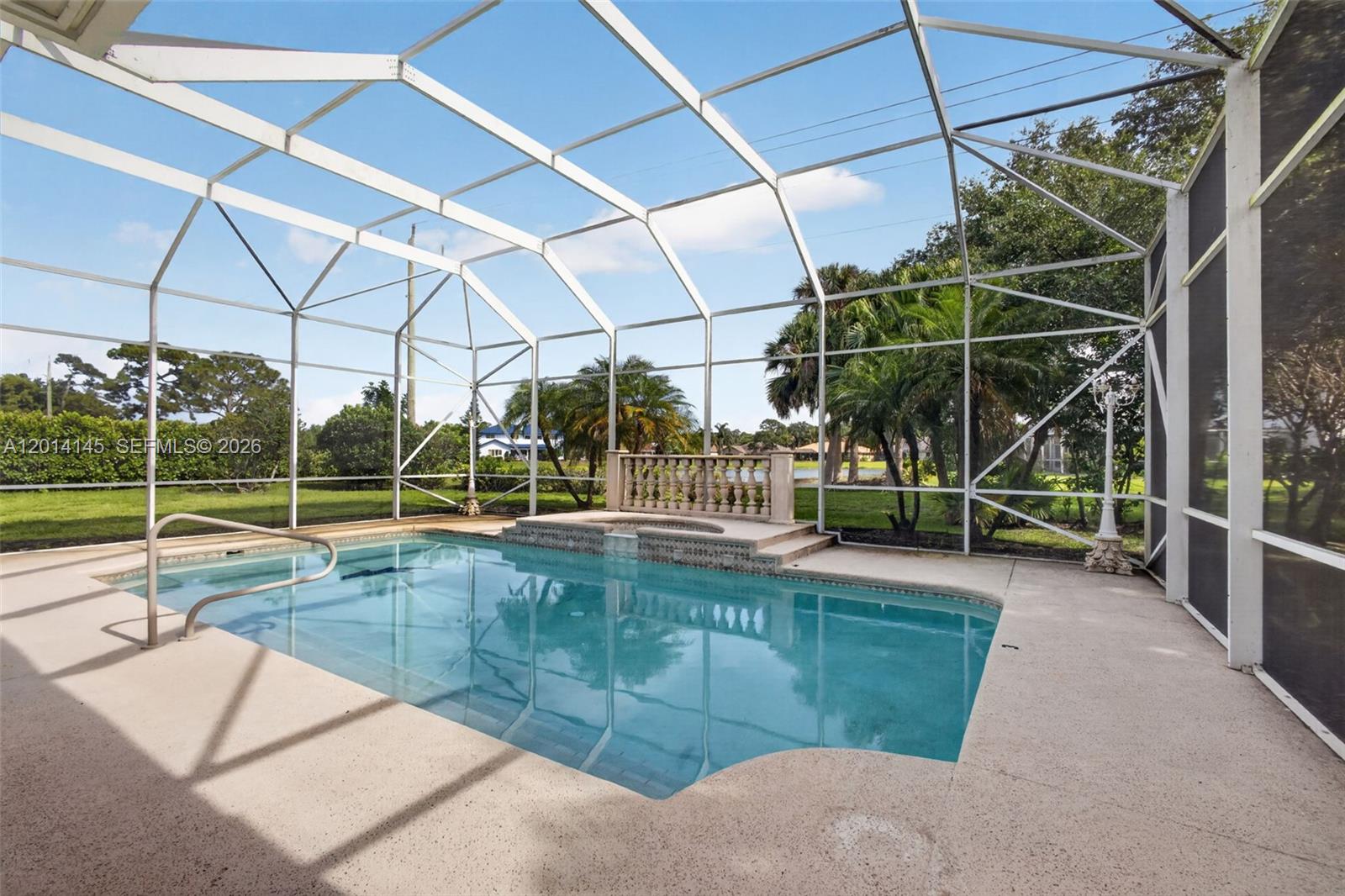A screened-in swimming pool with a raised spa and balustrade overlooks a grassy backyard — 19558 Red Gum Trl, Jupiter FL 33458, JUPITER, FL