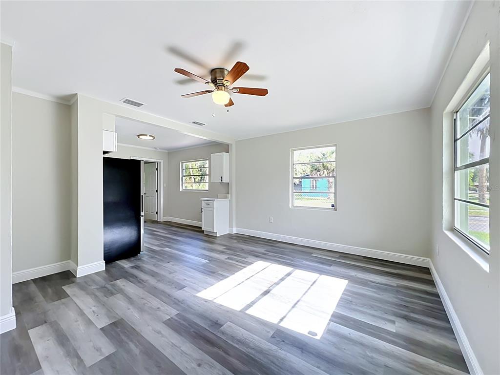 An open-concept living area features light gray walls, wood-look flooring, and a ceiling fan — 1500 S SUMMERLIN AVENUE, SANFORD, FL